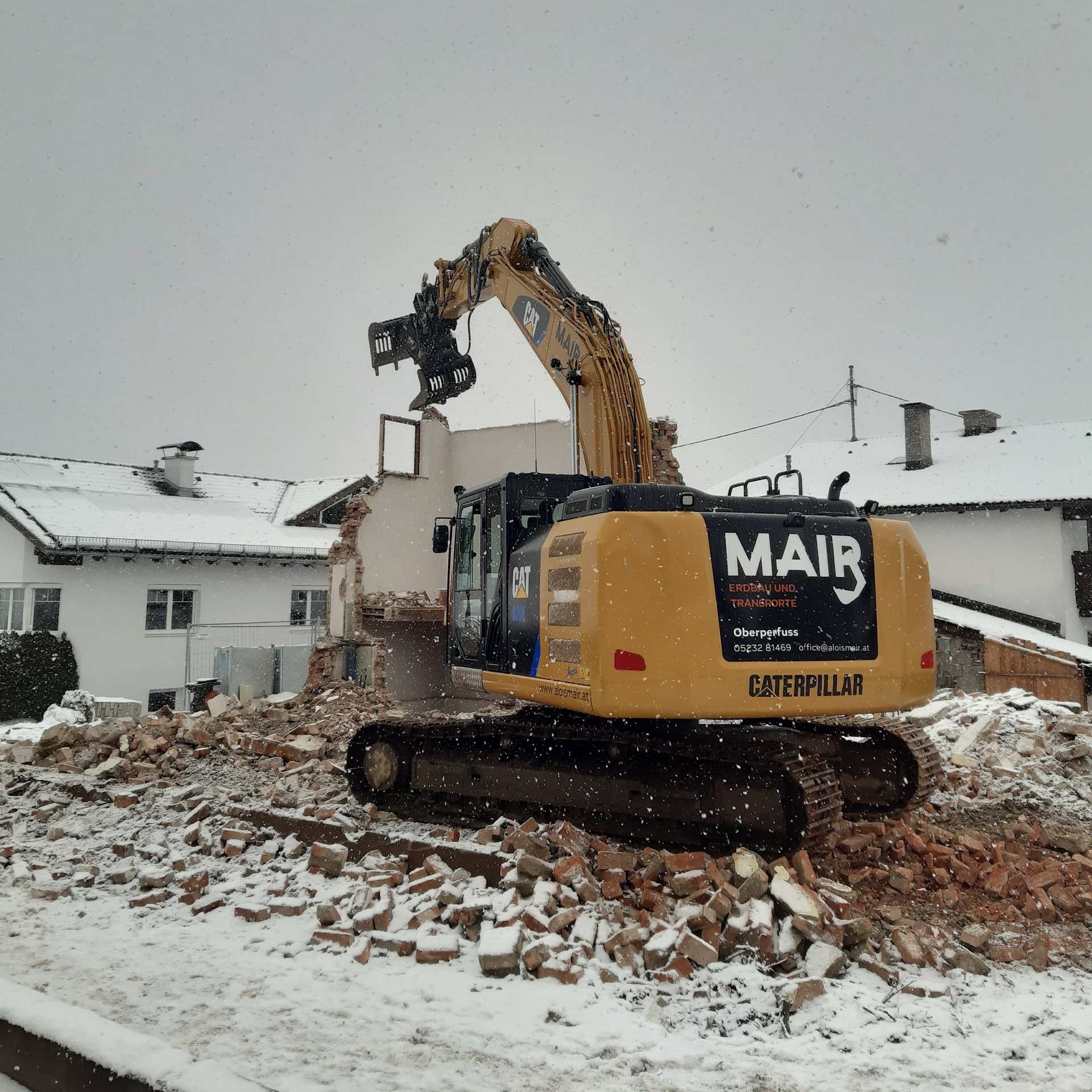Kettenbagger bei Abbrucharbeiten eines Hauses im Winter