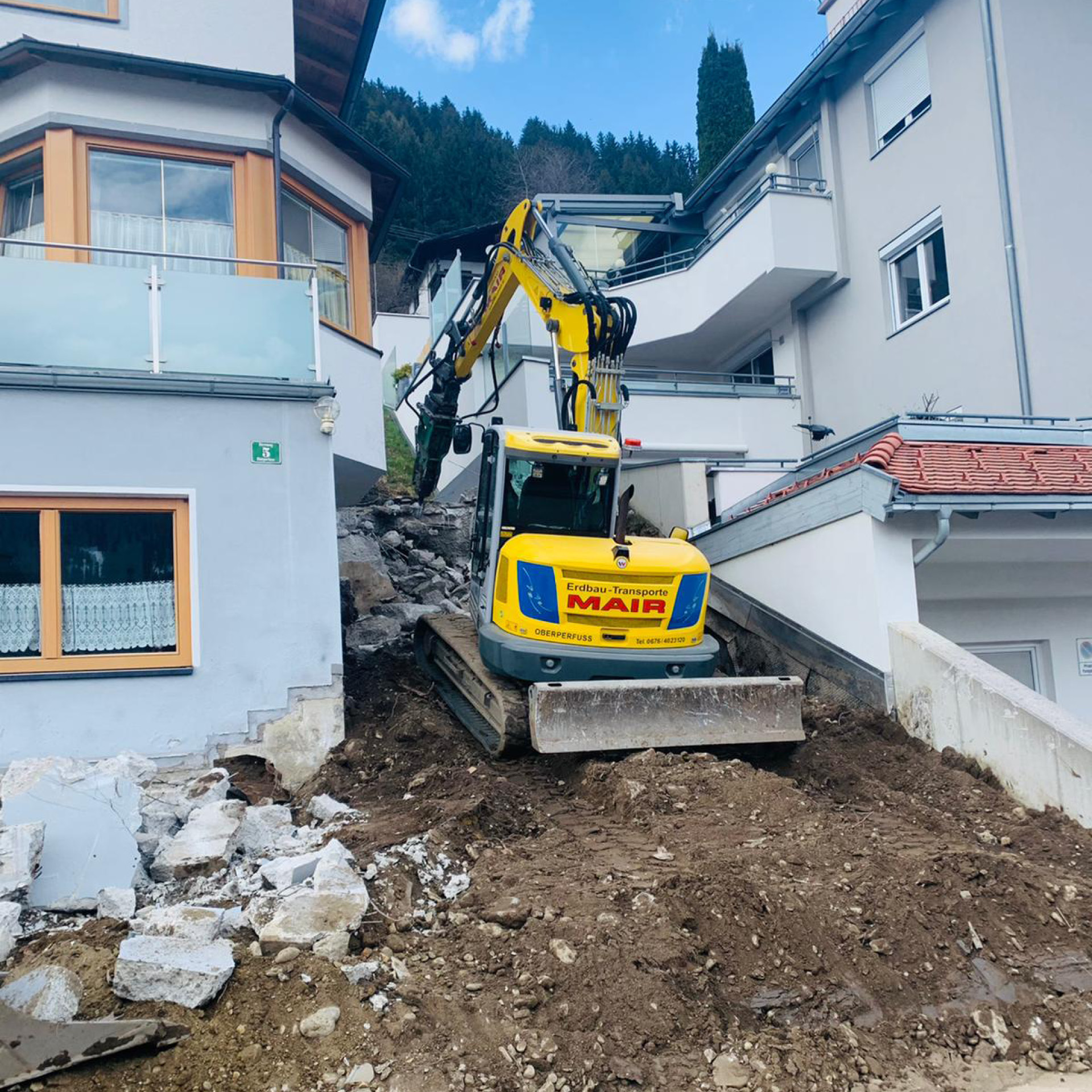 Kettenbagger bei Abbrucharbeiten einer Hausmauer