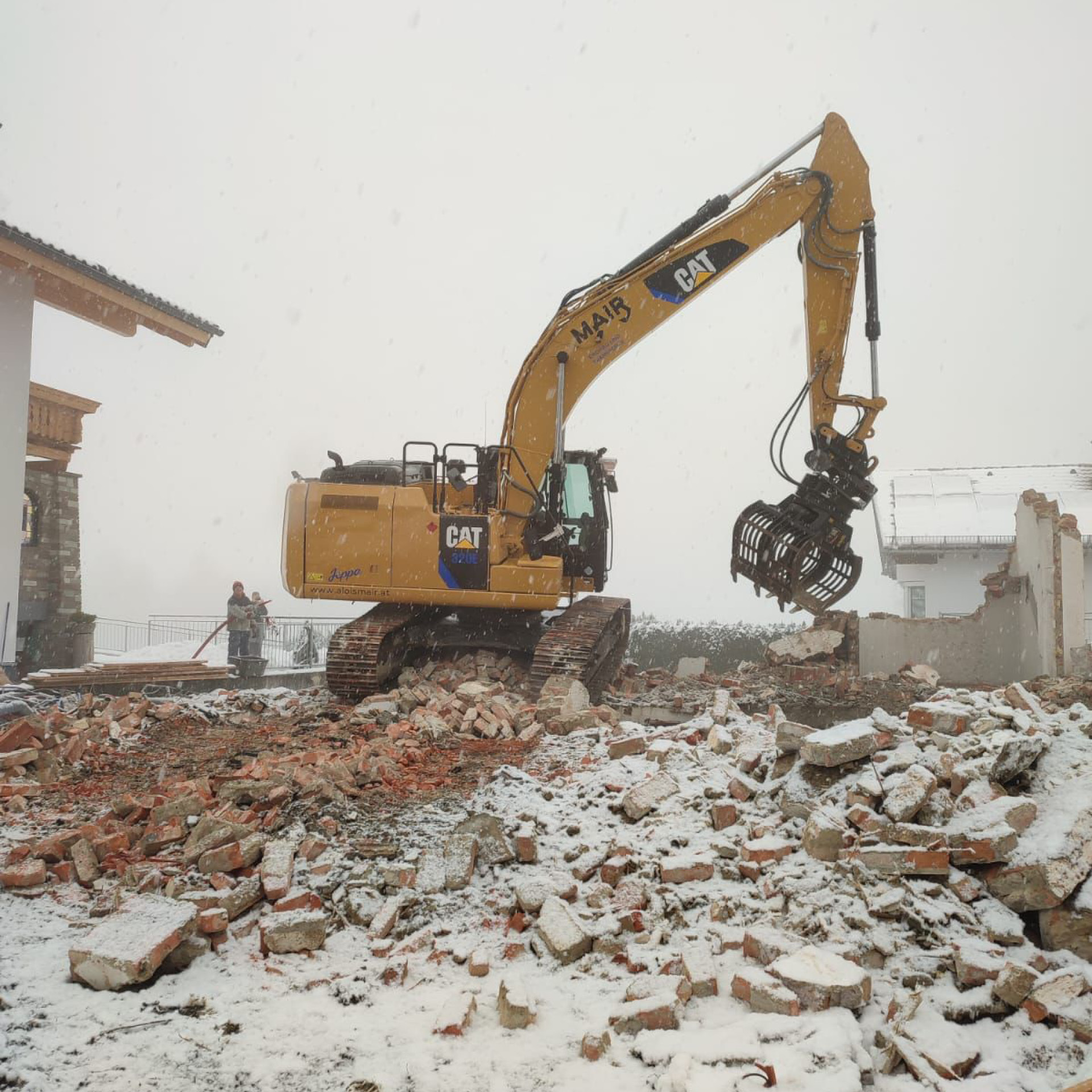 Kettenbagger bei Abbrucharbeiten eines Hauses bei Schneefall