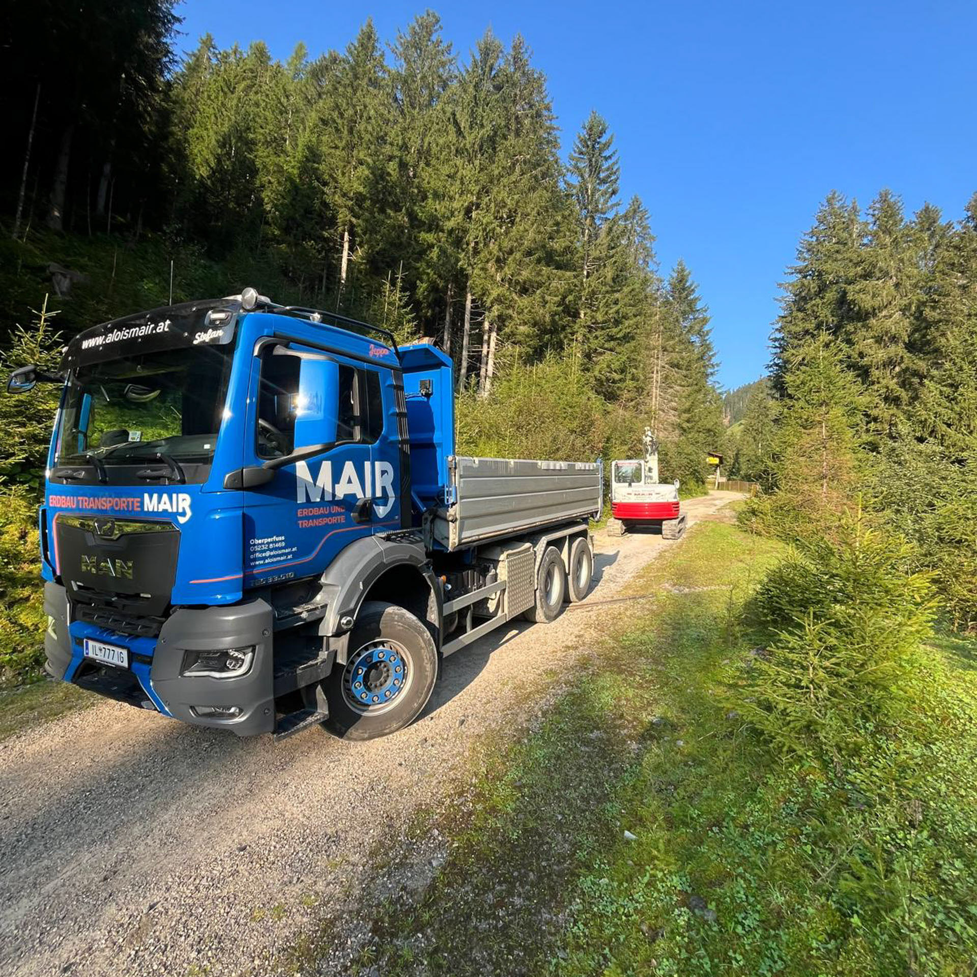LKW und Kettenbagger im Einsatz vom Wegbau