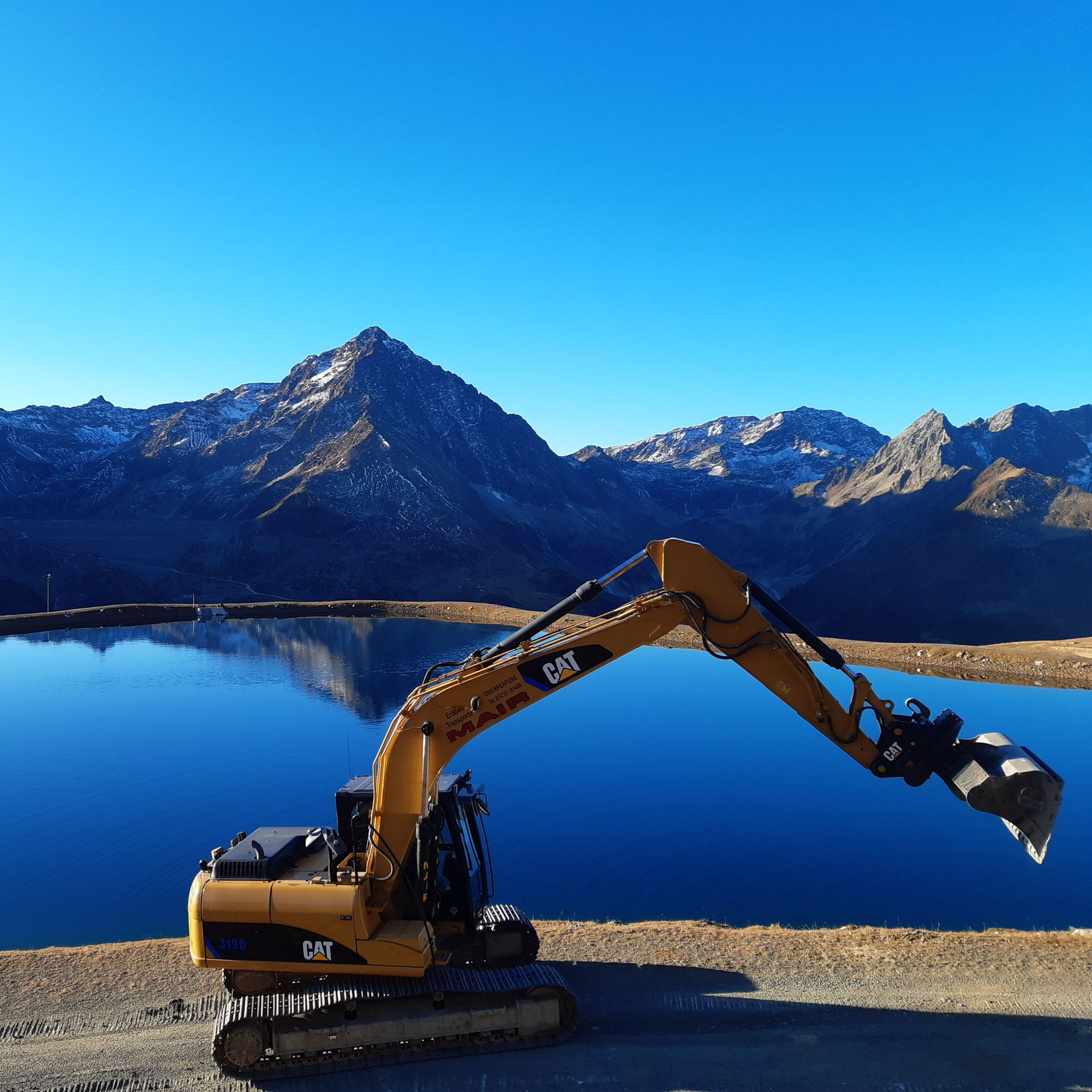 Kettenbagger vor einem See im Einsatz vom Wegbau