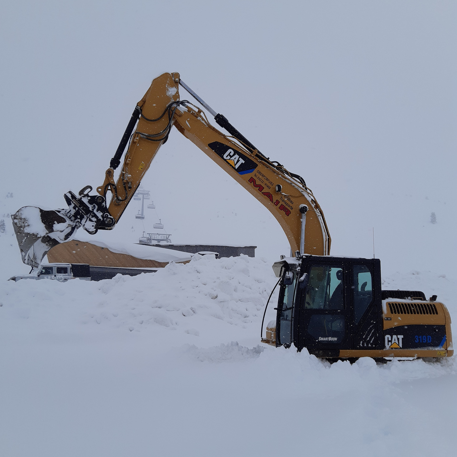 Kettenbagger im Schnee bei Lift- und Pistenbauarbeiten