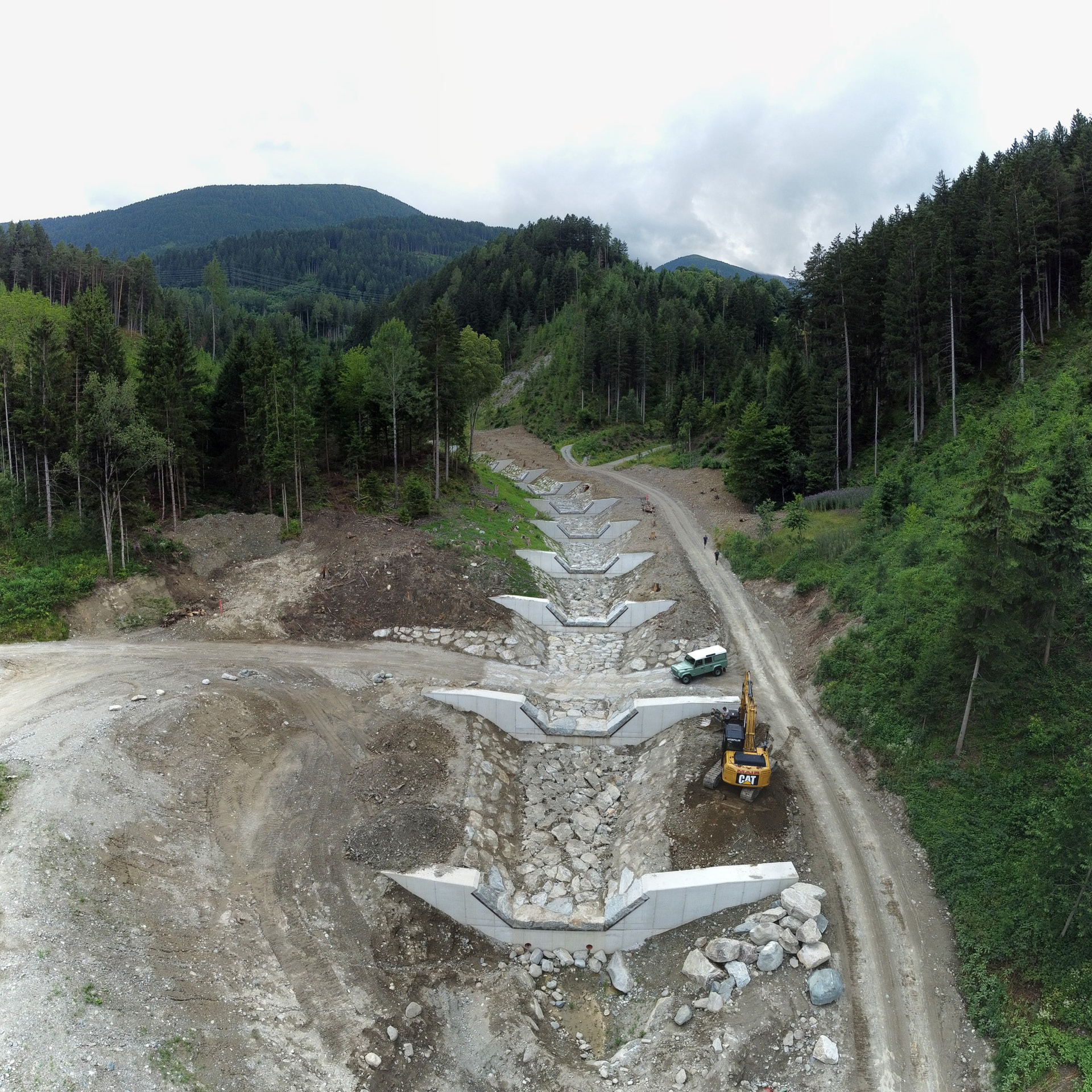 aloismair-wildbachverbauung Luftaufnahme einer Wildbachverbauung mit den einzelnen Stufen, ein Kettenbagger ist im Einsatz