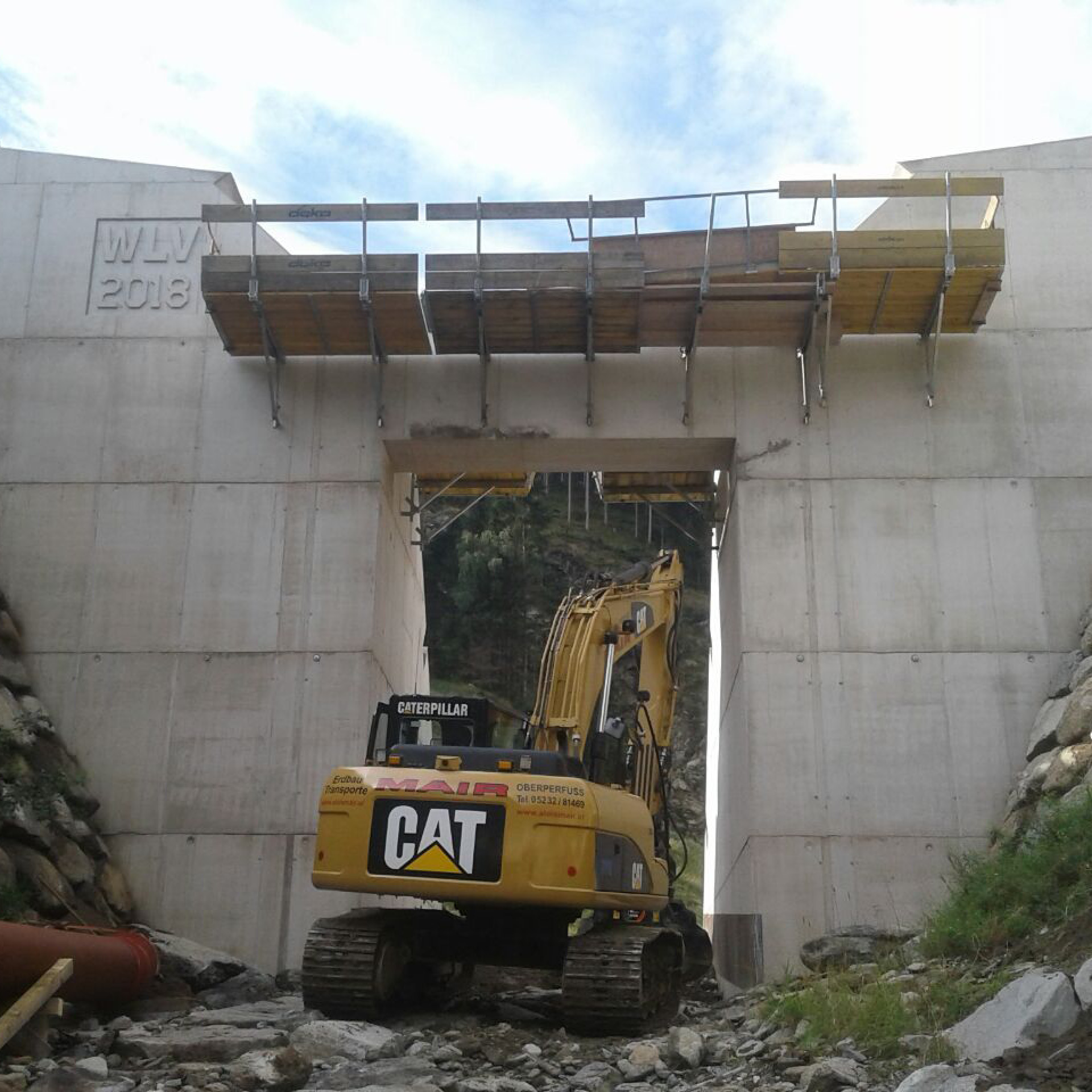 aloismair-wildbachverbauung10 Kettenbagger unter einer massiven Wasserschleuse der Wildbachverbauung