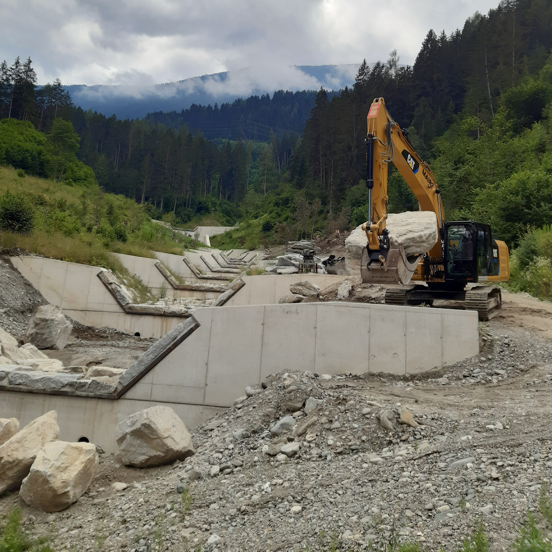 aloismair-wildbachverbauung5 Kettenbagger transportiert einen großen Stein für die Wildbachverbauung, mehrere Wasserschleusen